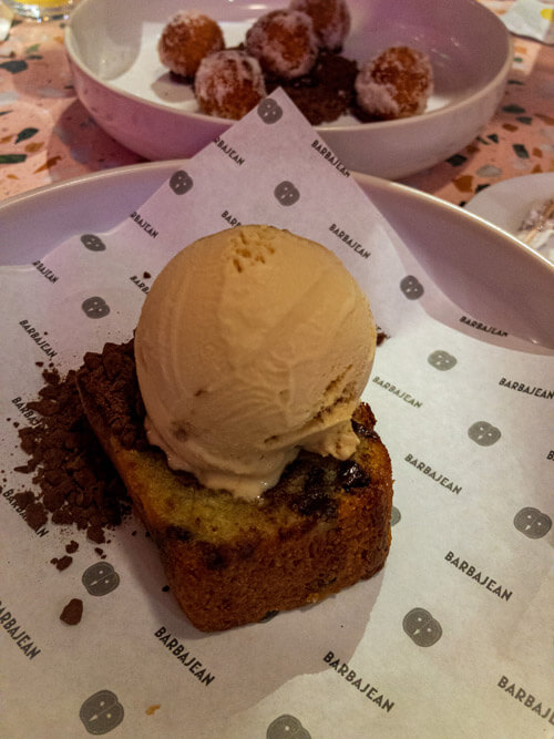 Banana bread topped with ice cream drizzled with chocolate chips