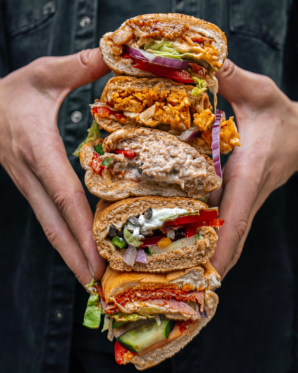 A collection of subway sandwiches stacked on top of each other.