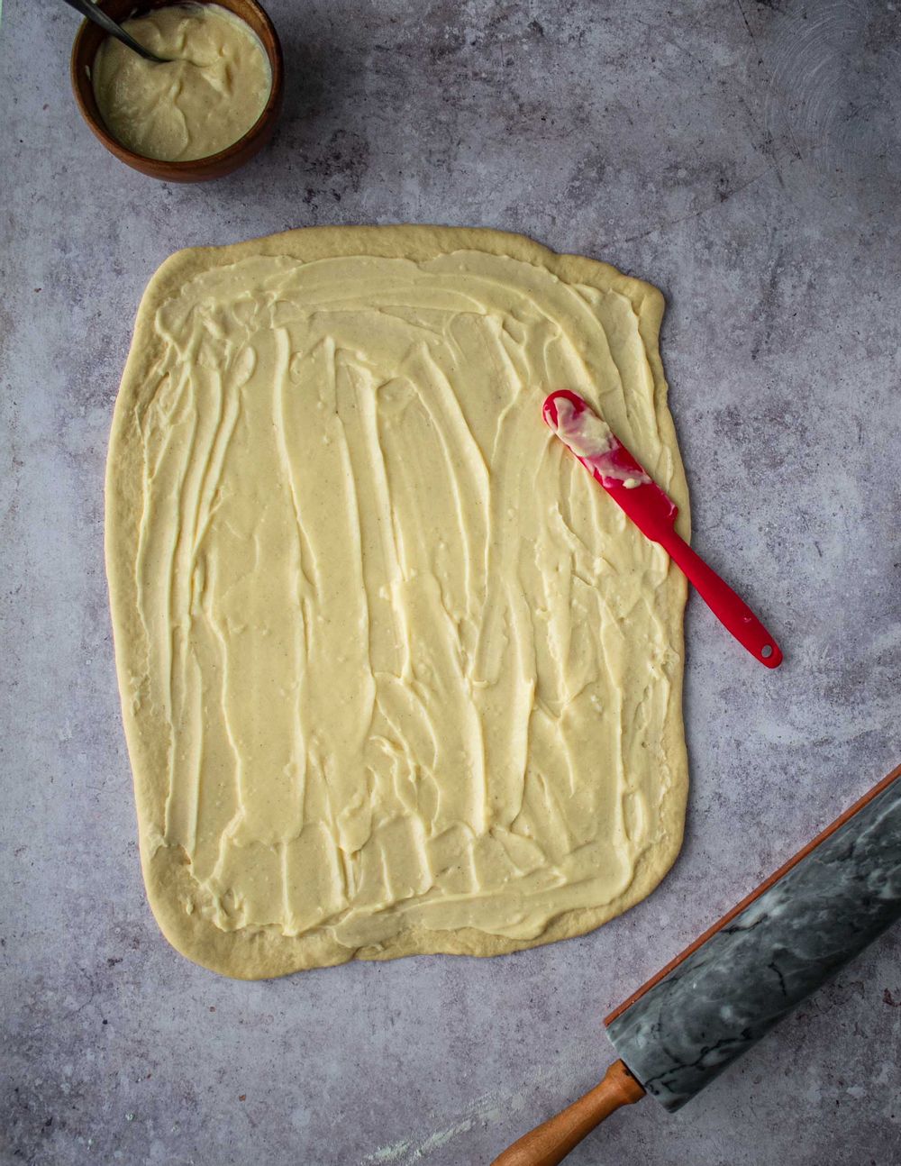 Spread cream over pastry before rolling it into buns