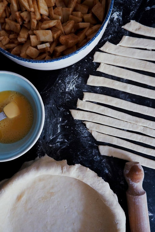 All the ingredients needed to prepare a traditional apple pie, including stewed apples, butter, short-crust pastry base and short-crust pastry trimmings