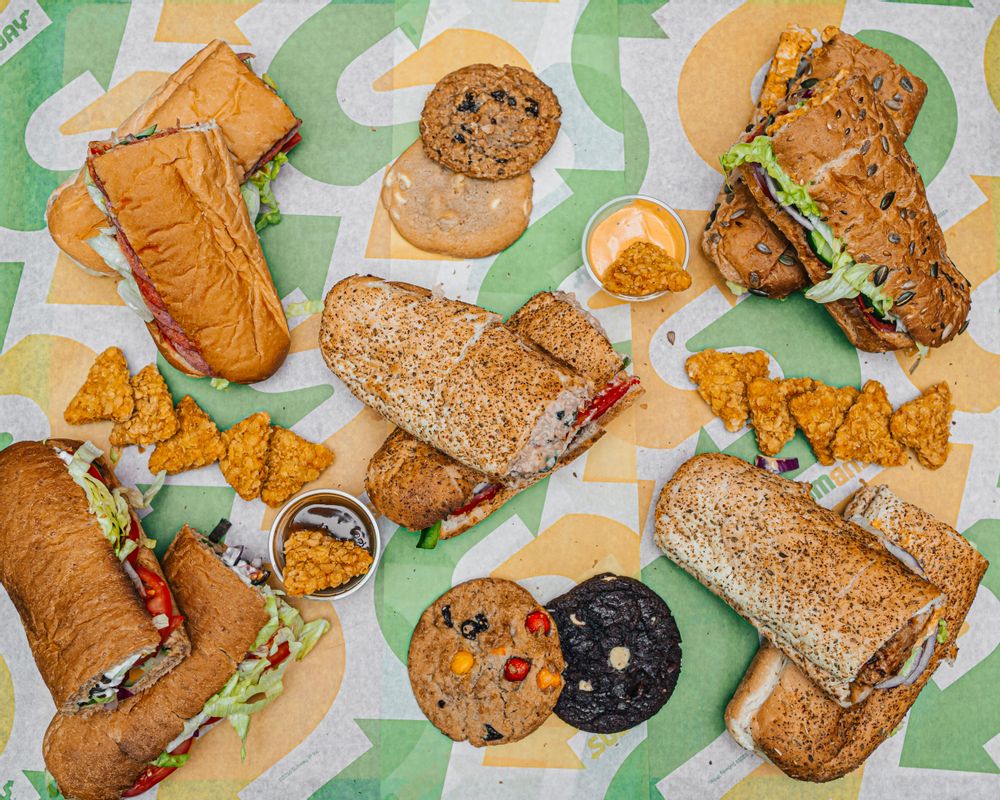 Subway spread including sandwiches, cookies and nibbles with dip