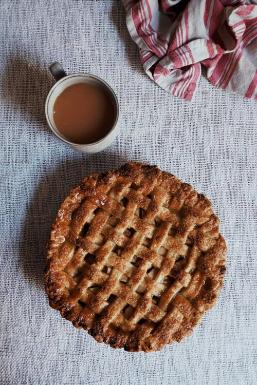 The finished apple pie with a beautiful golden brown colour accompanied by a cup of tea