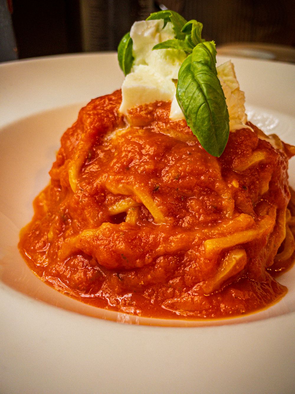 Spaghetti with a red tomato sauce topped with ripped bufola mozzarella. 