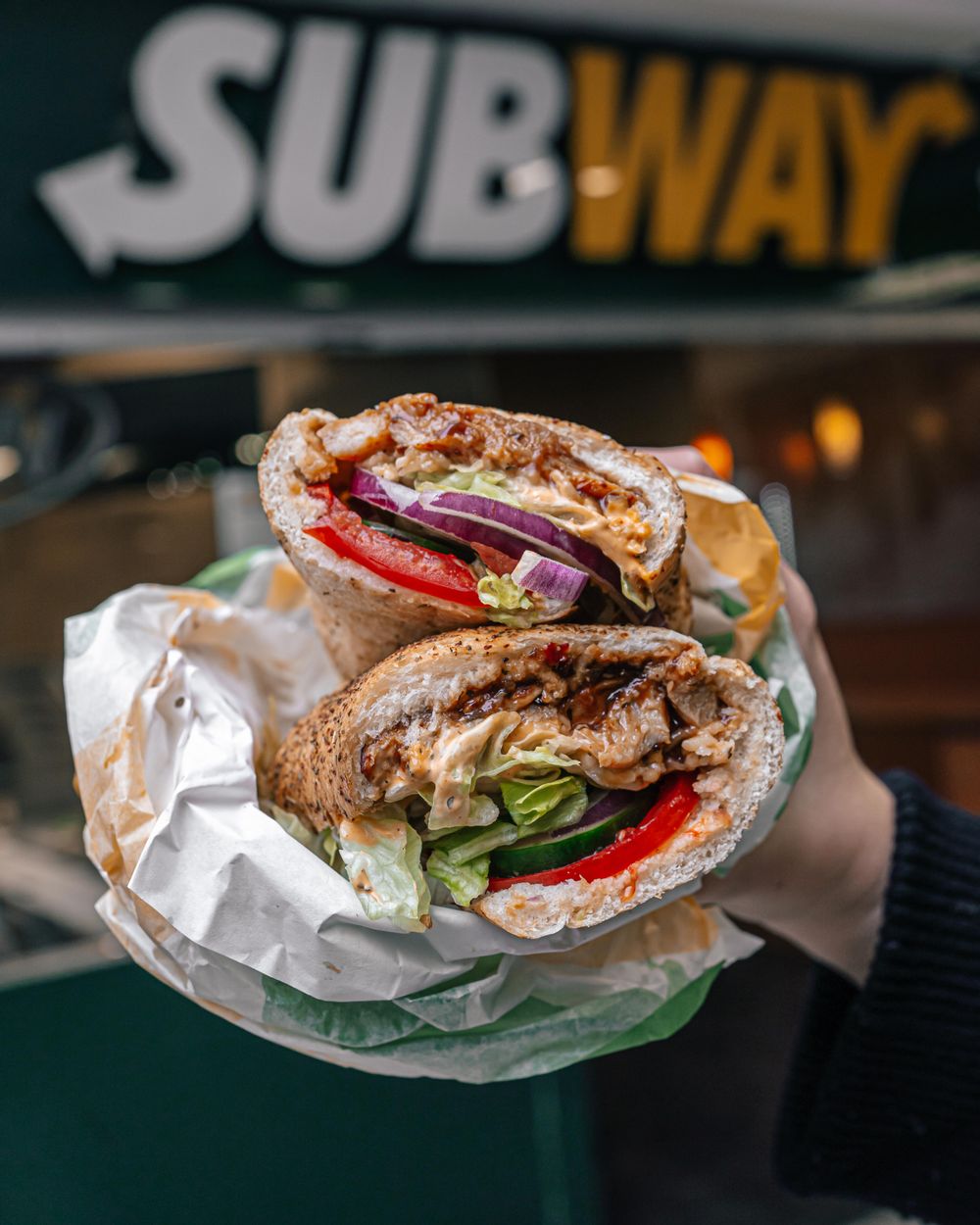 A subway sandwich with fresh onion, tomato, lettuce, sauce and chicken.